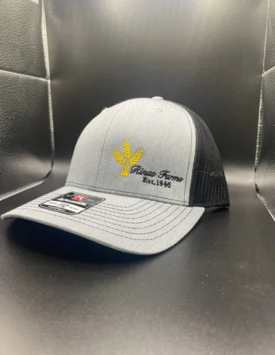Gray baseball cap with black mesh back featuring a yellow wheat emblem and "Rinse Farms Est. 1948" embroidered on the front panel.