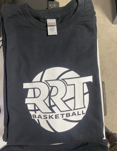 Folded black t-shirt with "RRT Basketball" logo in white, featuring a stylized basketball design, brand tag "Gildan Heavy Cotton" visible.