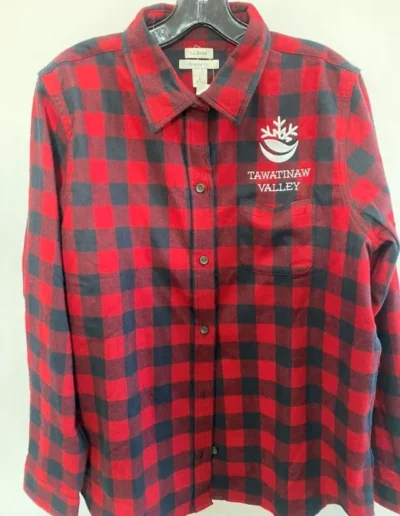 Red and black checkered flannel shirt on hanger with "Tawatinaw Valley" and a logo embroidered on the left side.